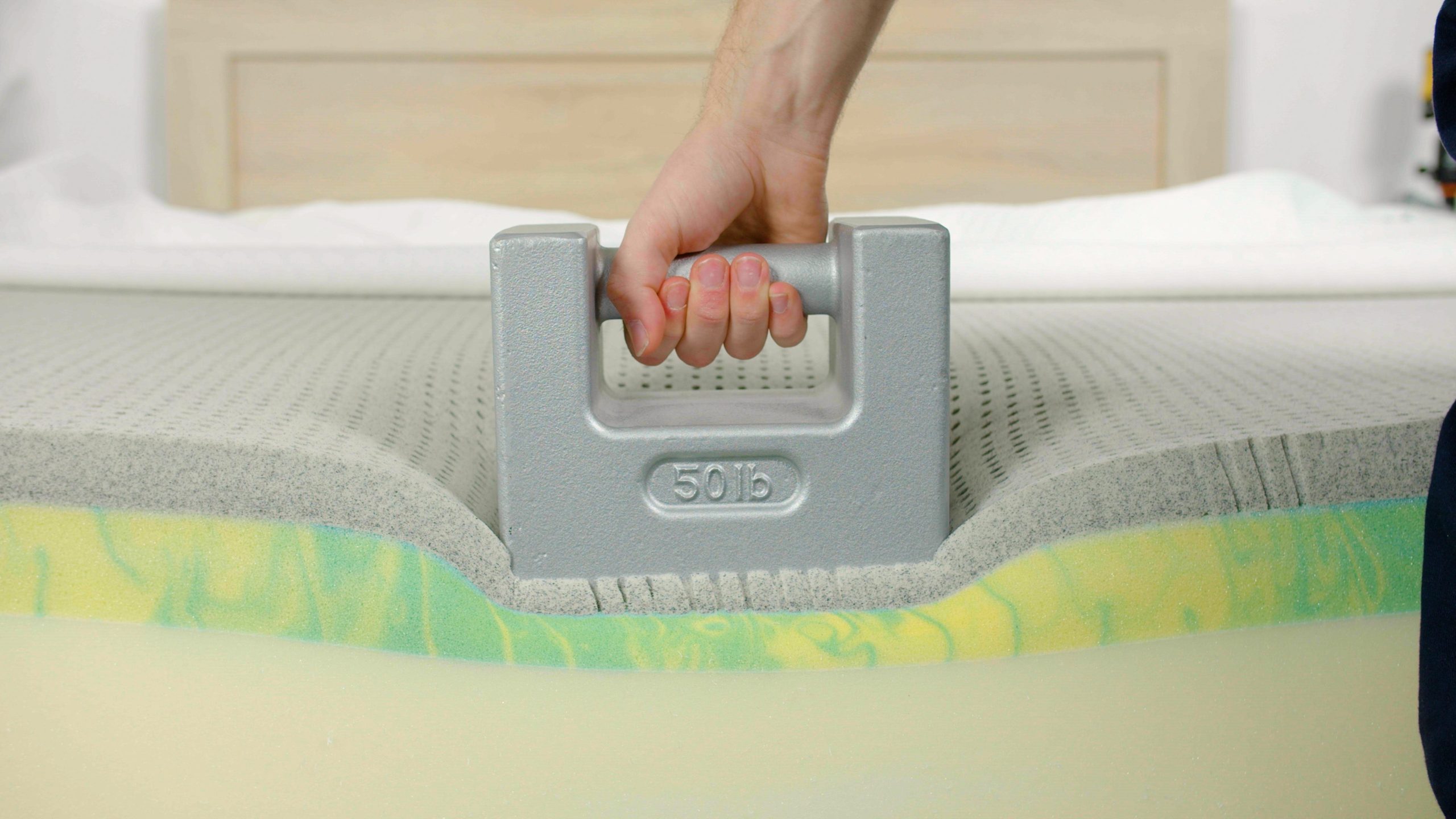 Tester uses a weight to test edge support on the GhostBed Classic