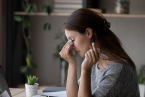 Woman in dim light rubbing forehead