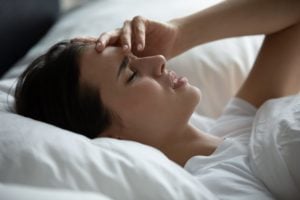 Woman lying in bed, looking worried