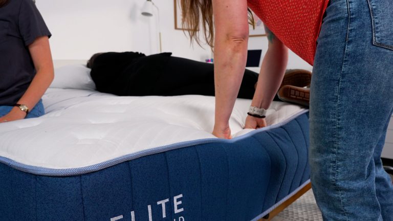 Sleep Foundation tester pressing into the Bear Elite Hybrid mattress to assess responsiveness and firmness