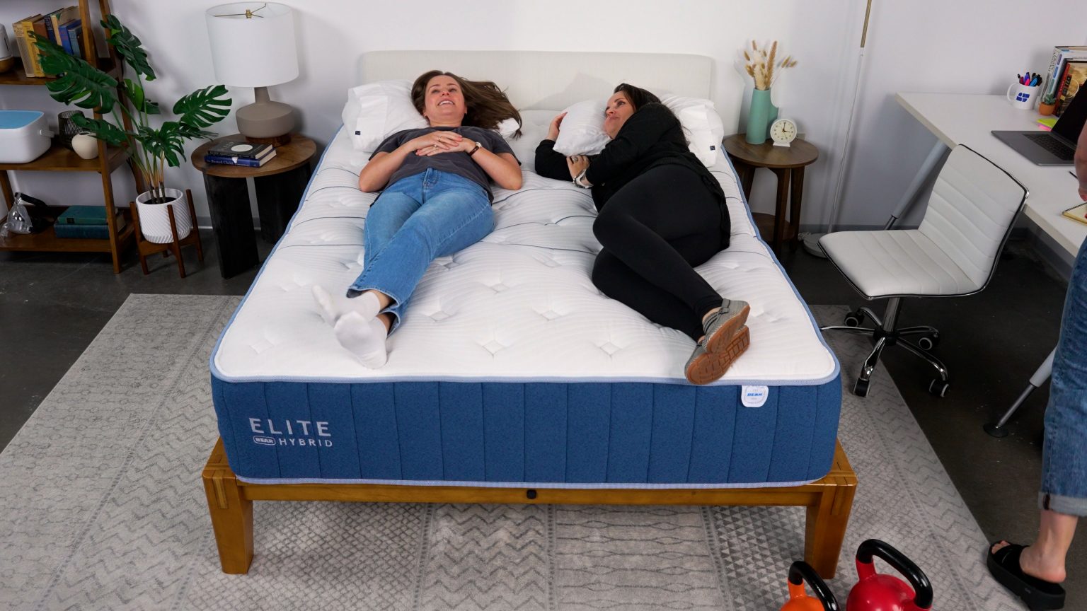 Two Sleep Foundation testers lying on the Bear Elite Hybrid mattress in different sleep positions