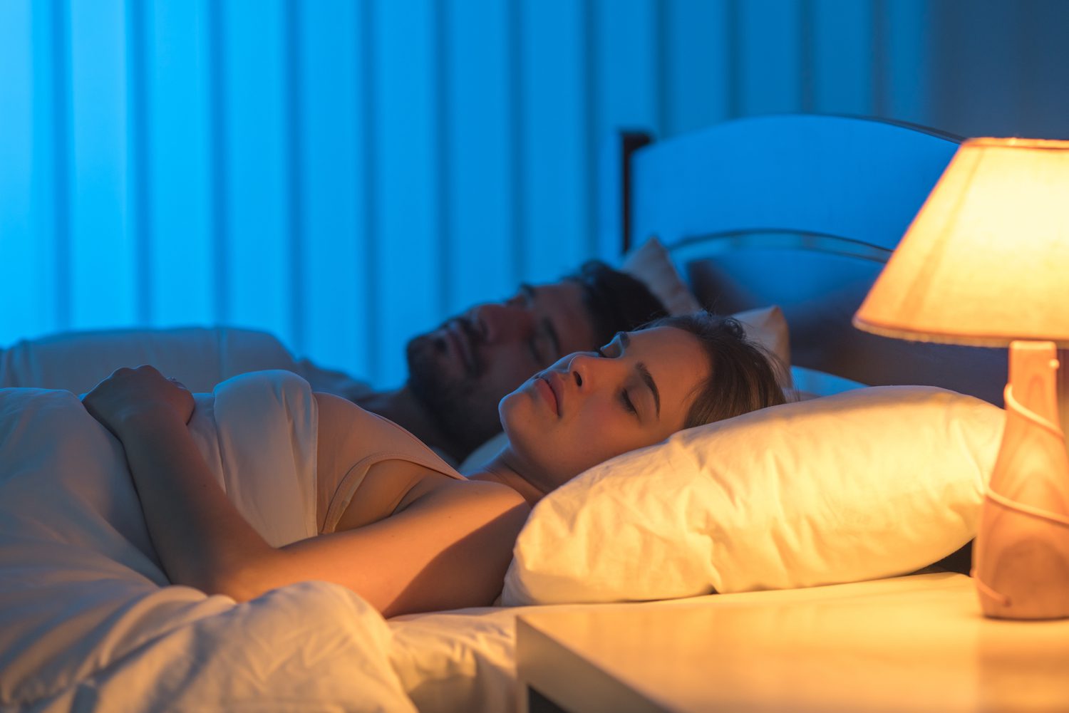 couple asleep in bed with lamp on