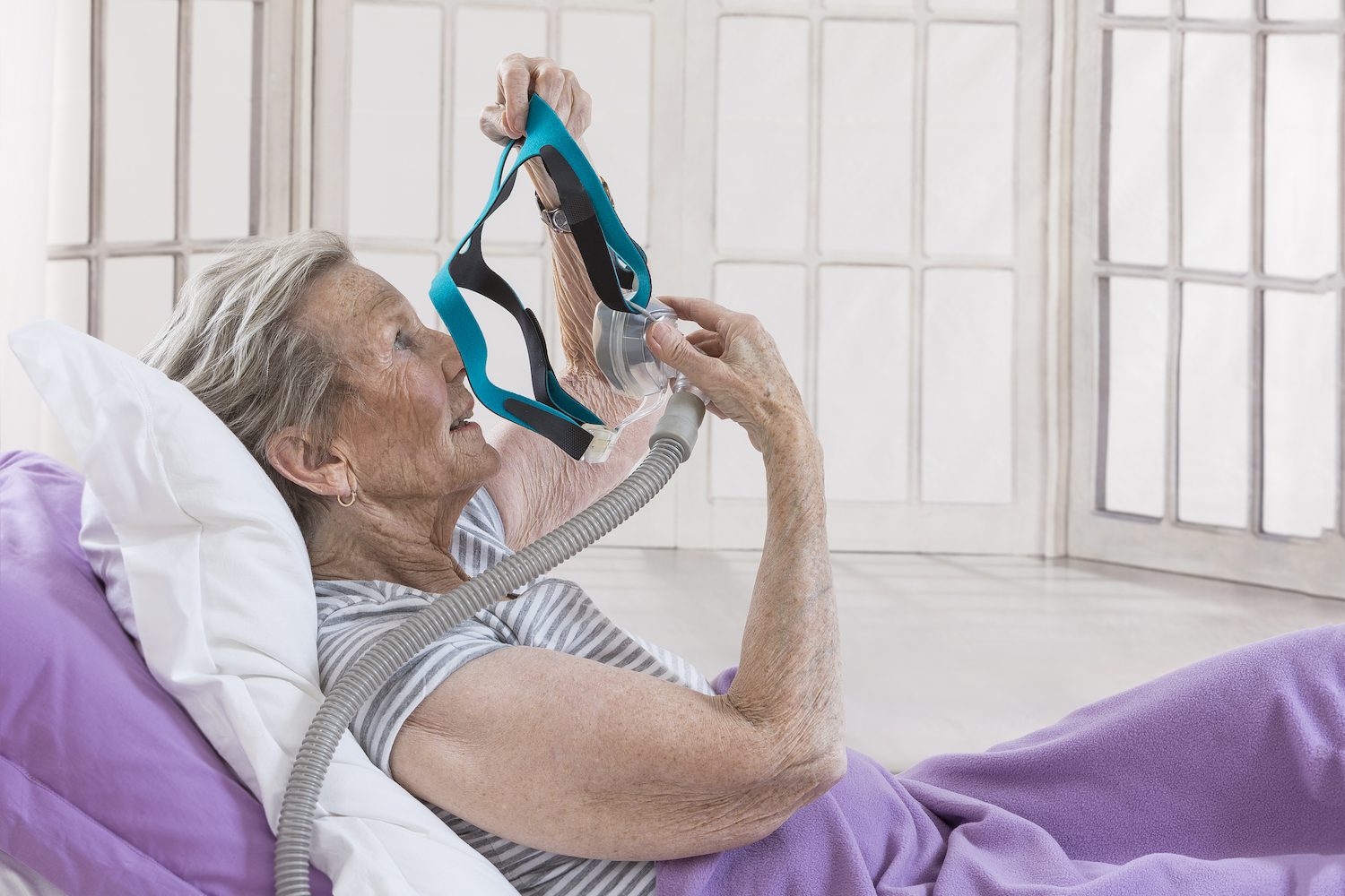 Woman using her CPAP machine in bed.