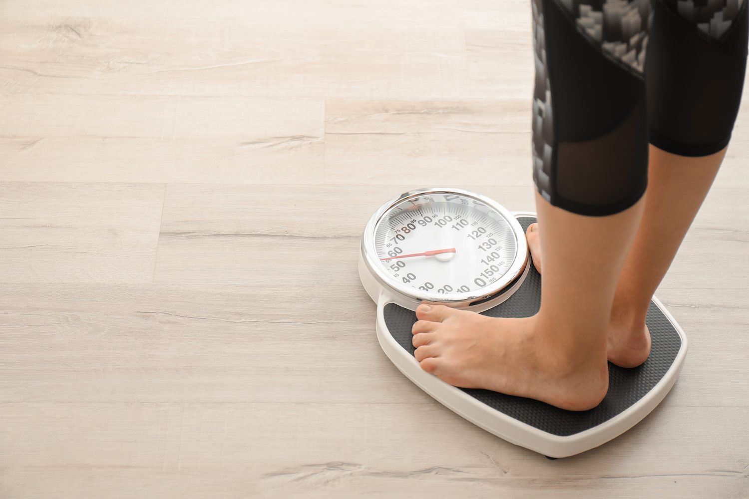 Two feet appear on a scale as a person checks weight
