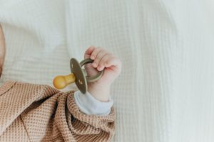 A newborn holding a pacifier