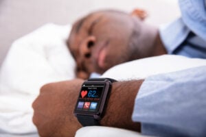 Man Sleeping With Smart Watch Heart Monitor on his Wrist.