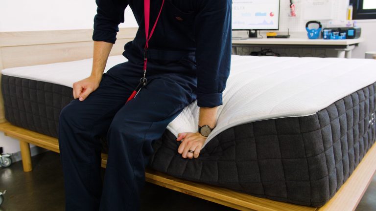 Sleep Foundation tester sitting on the Helix Plus mattress to evaluate edge support