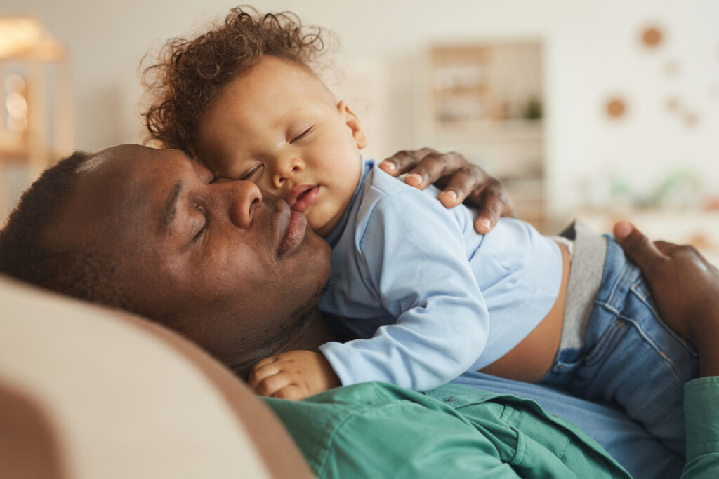 Side view portrait of loving African-American dad embracing baby son.