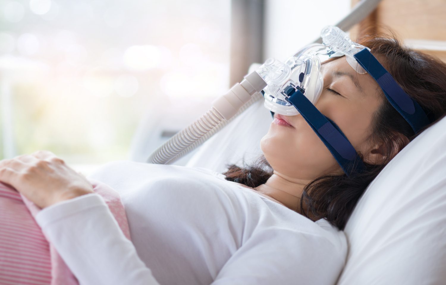 A woman sleeps peacfully while using a CPAP machine.