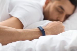Person sleeping with a sleep tracker on their wrist
