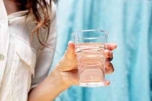 woman holding a glass of distilled water