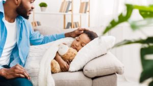 stock photo of a child being tucked in by father