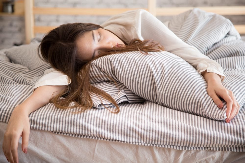Stock photo of an exhausted woman lying asleep in bed