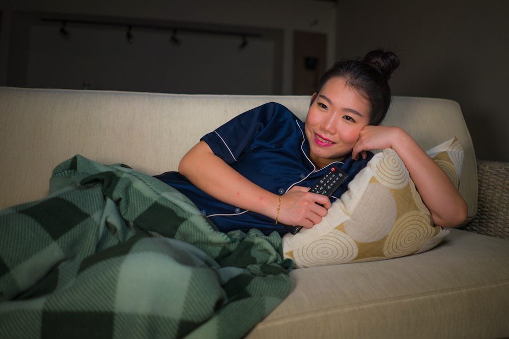 stock photo of a woman watching TV in her pajamas