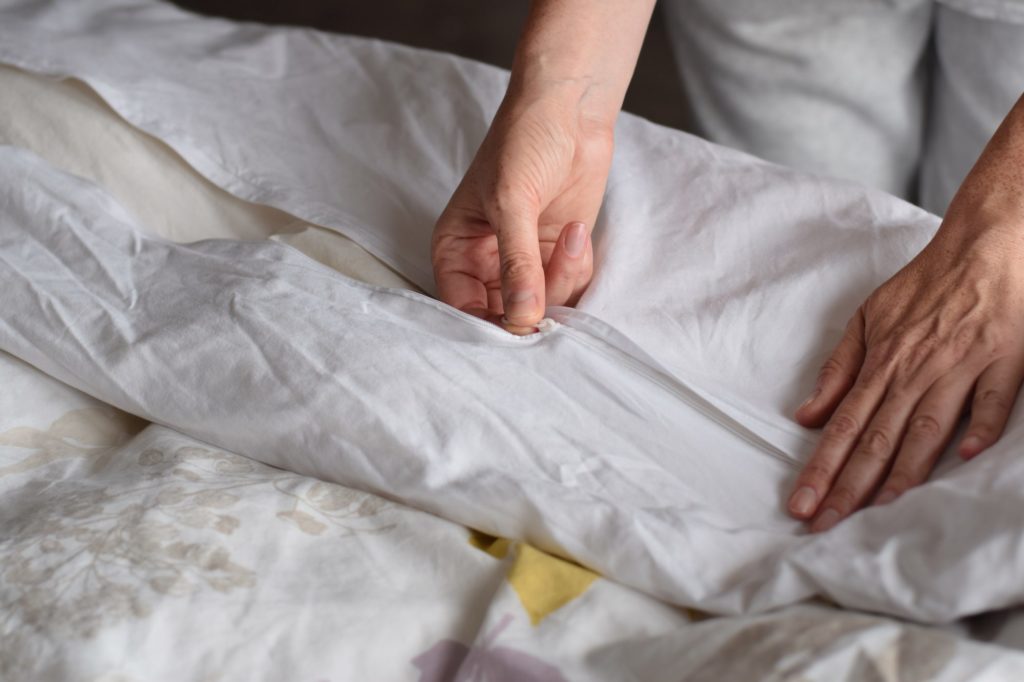 stock image of woman putting on a duvet cover