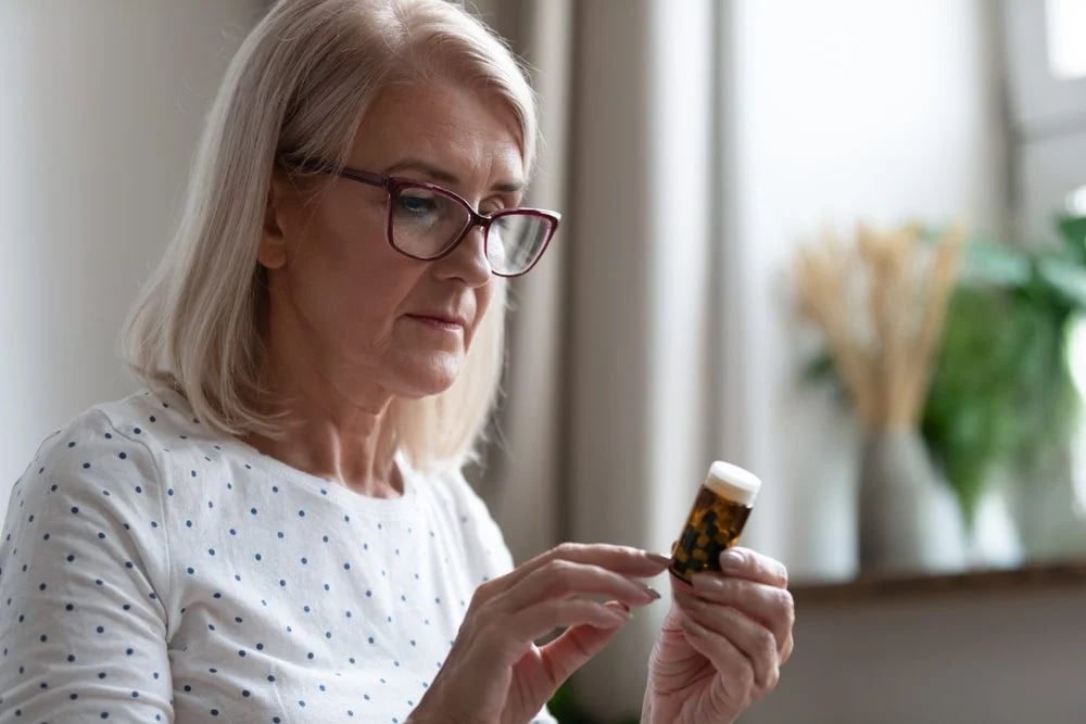stock photo of a woman looking at the label on a bottle of pills