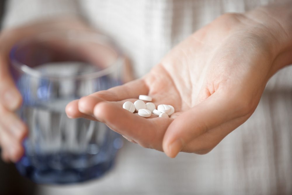 stock photo of a person holding pills and a glass of water