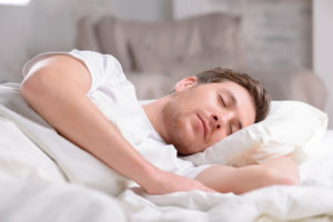 A young man sleeps peacefully underneath blankets