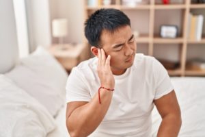 A young man holding his ear with a pained expression