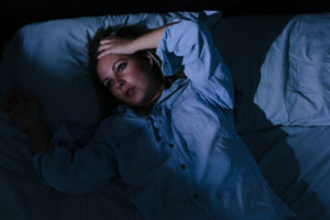 A woman in bed runs her hands through her hair