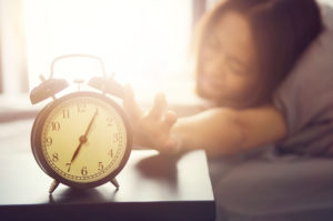 woman reaching to turn off alarm clock