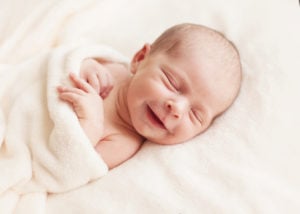 A newborn baby smiles while sleeping