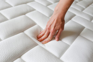 Cropped shot of young woman's hand testing white mattress