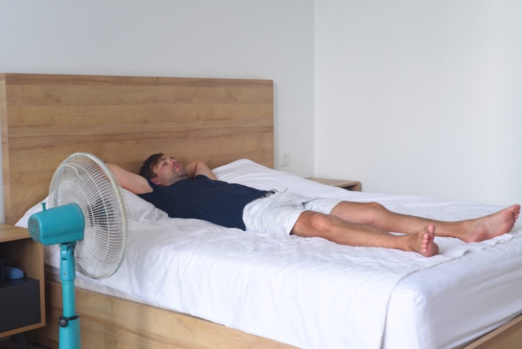 A picture of a man sleeping with a fan on