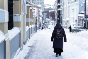 An elderly woman walks through a snow-covered street