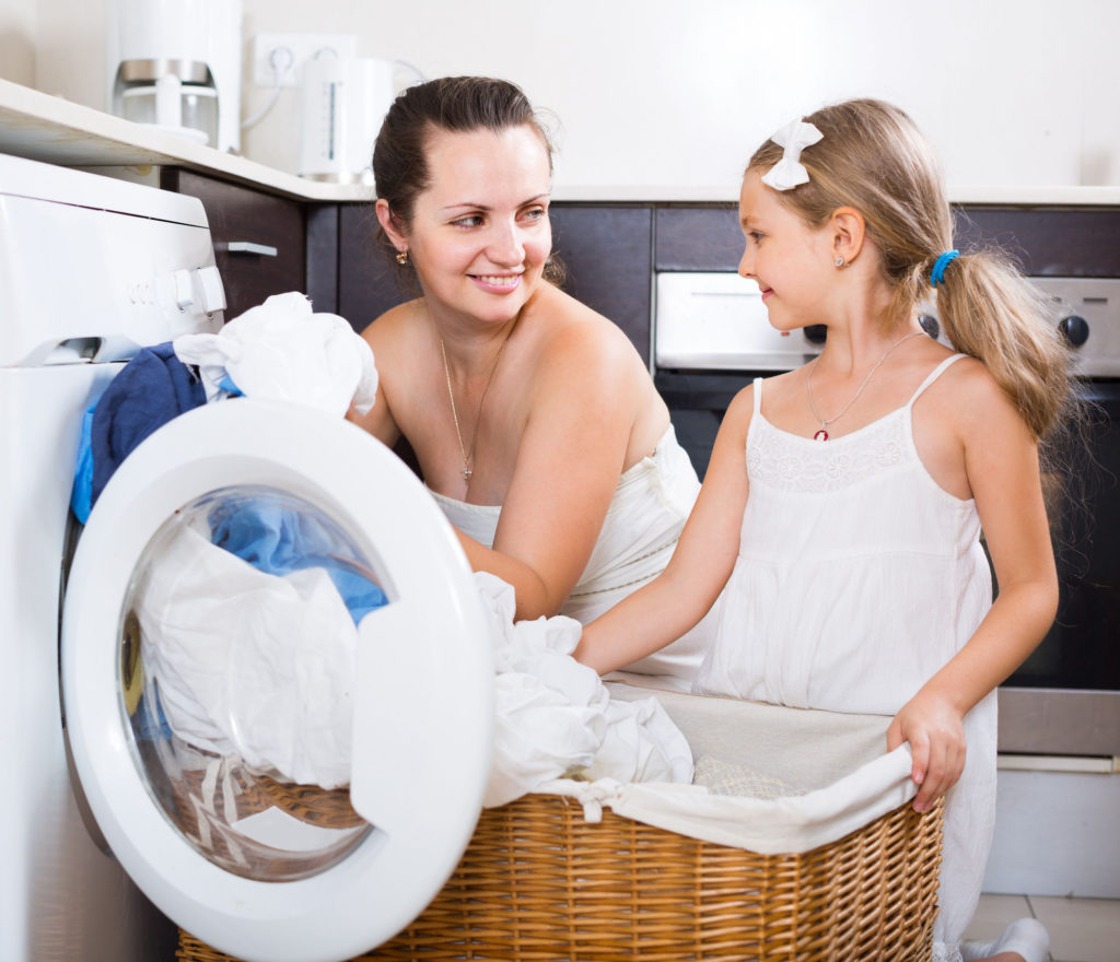 woman and child washing sheets with a washing machine