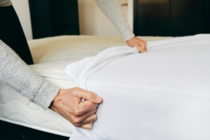 Closeup of a young man placing a mattress cover on a mattress