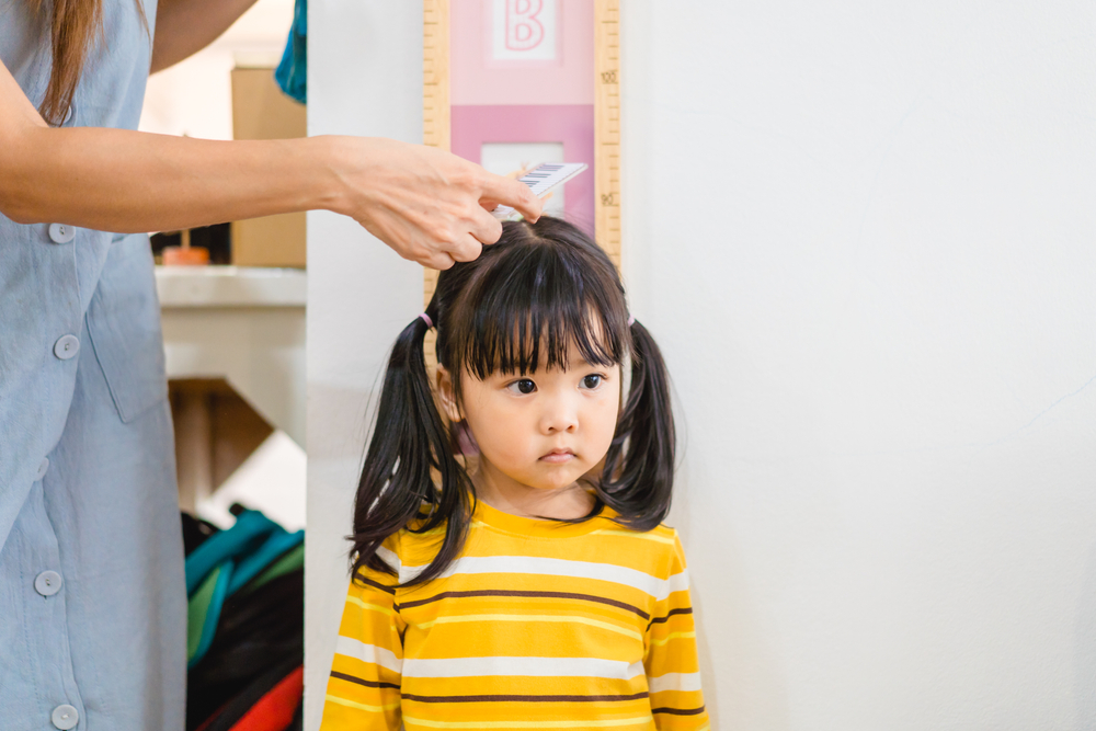 Mother measuring the height of her daughter