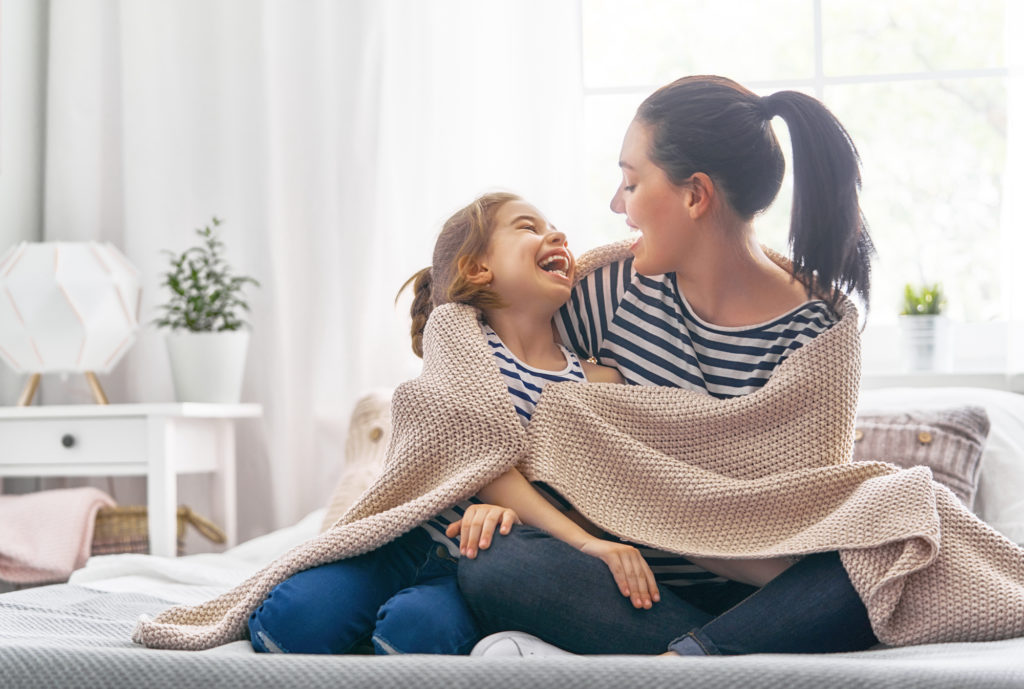 Woman and child under coverlet