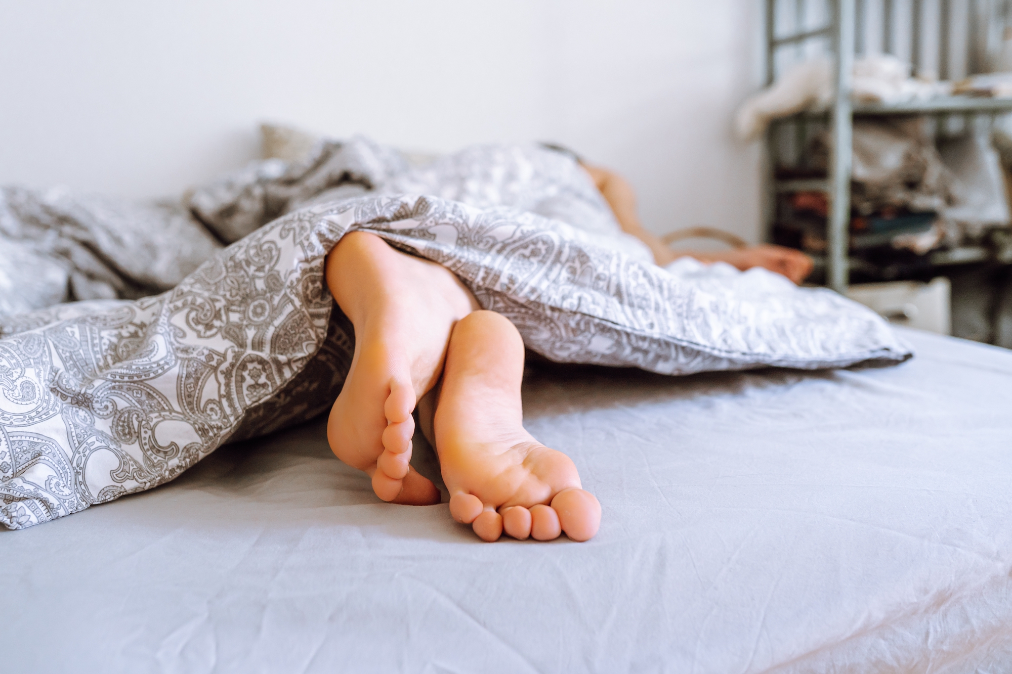 https://www.sleepfoundation.org/wp-content/uploads/2023/05/feet-sticking-out-from-comforter.jpg