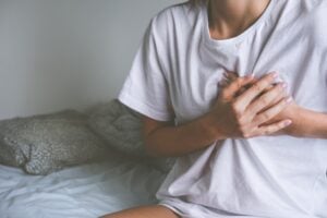 person holding their chest because of heart palpitation