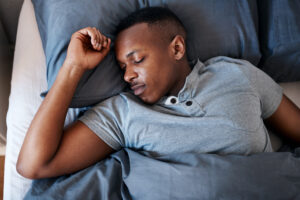 A young man struggling to sleep in bed.