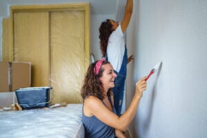 Two women painting a bedroom