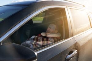 A man sleeps in a car with the seat reclined