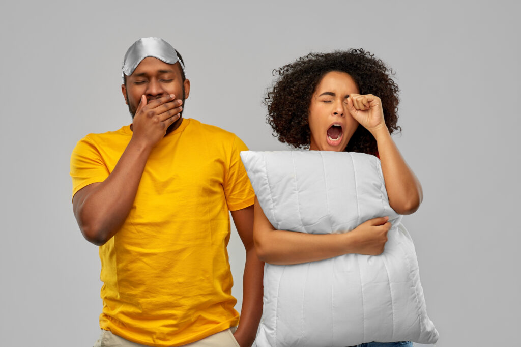 couple yawning with sleep mask and pillow